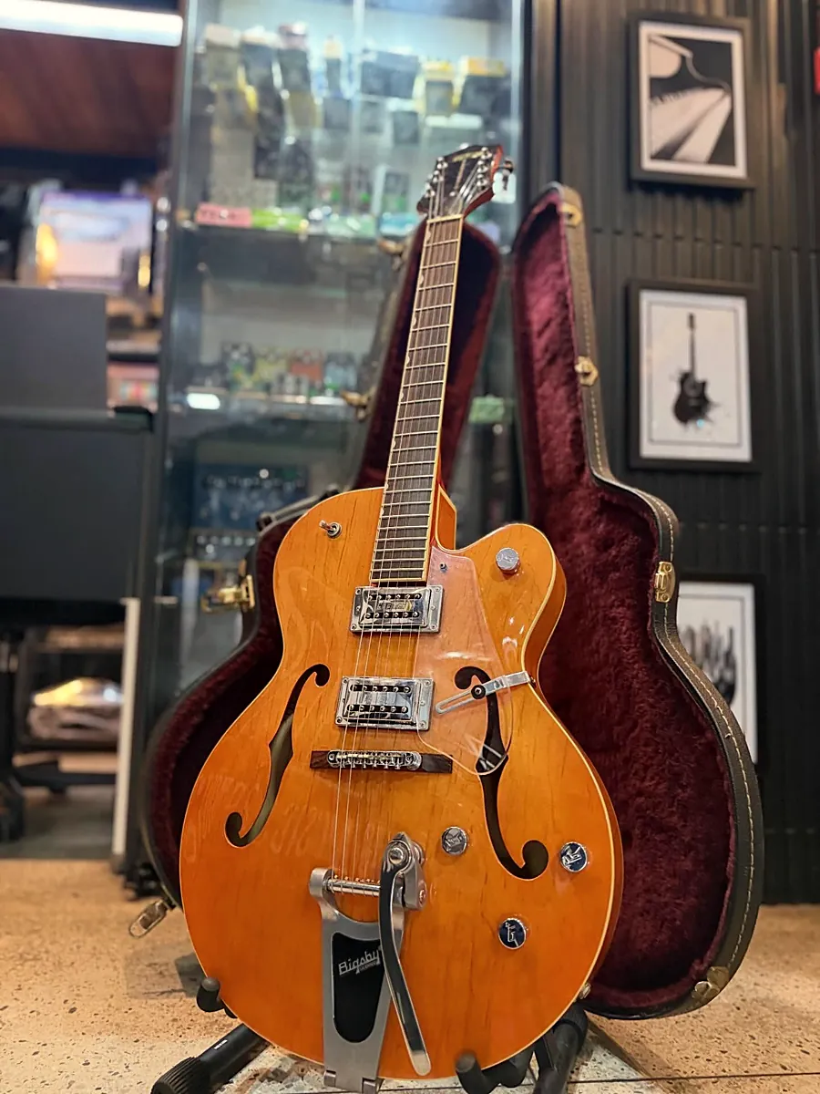 Guitarra Gretsch laranja ao lado do case