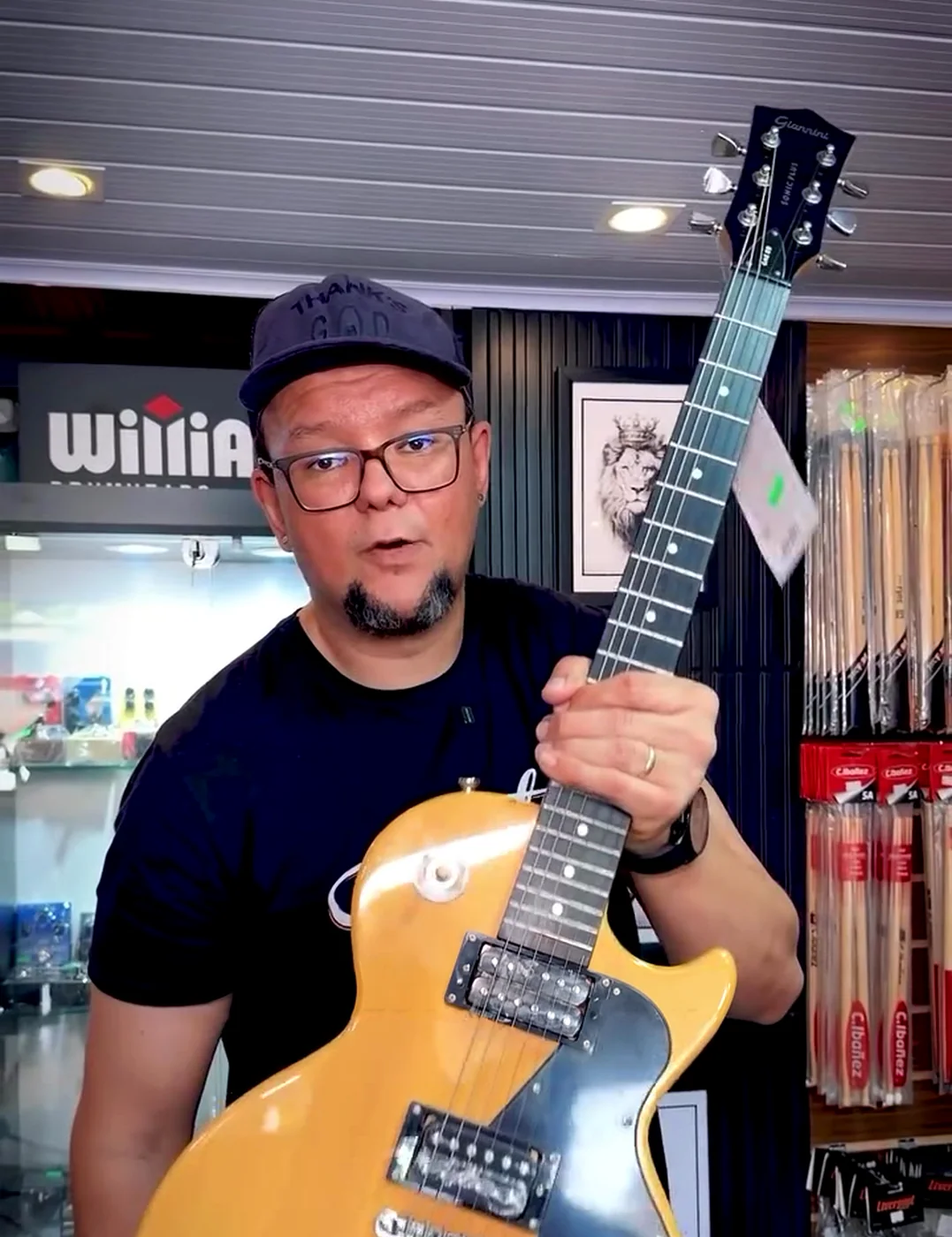 Igão na loja segurando uma guitarra Les Paul amarela